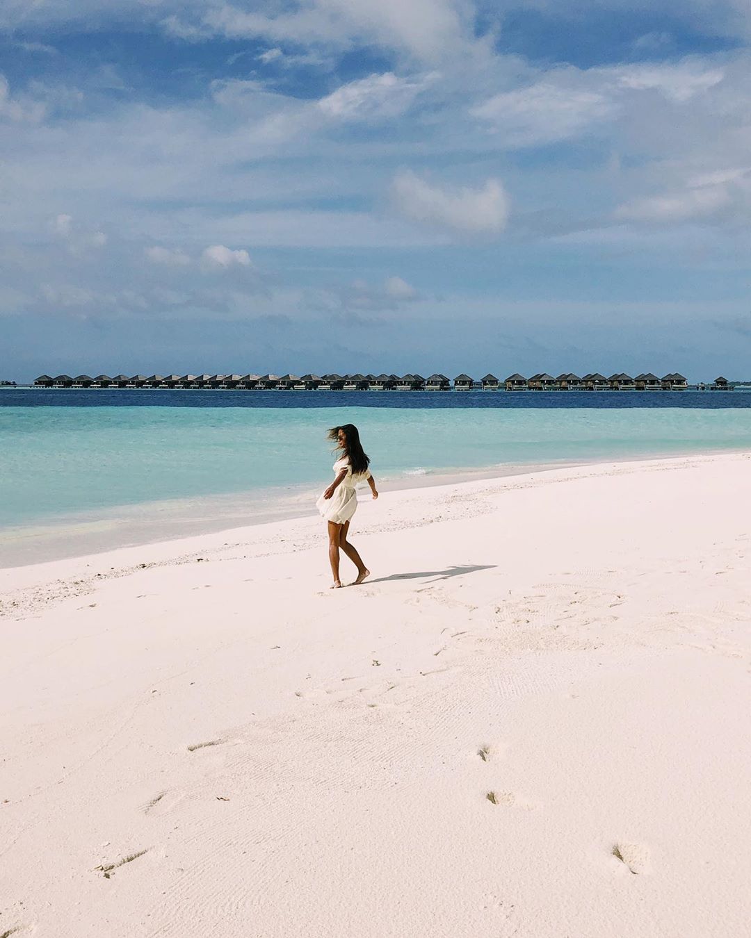 Woman Walking on a White Sand Beach. Photo by Instagram user @misselectrify
