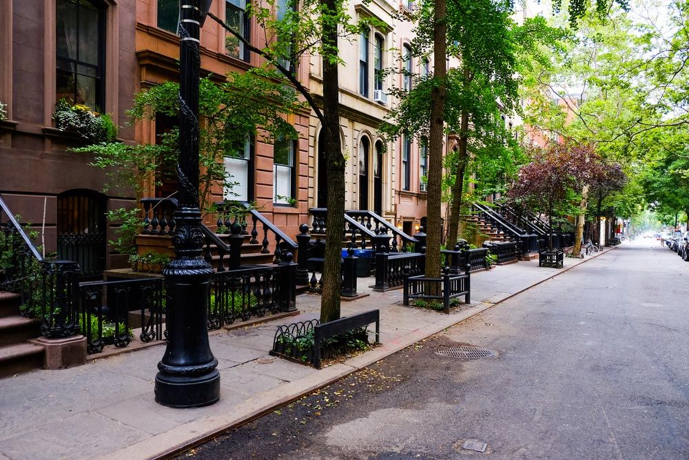 Greenwich Village street with brownstone buildings and trees lining sidewalks