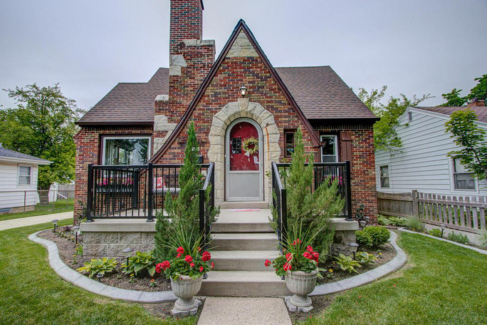 Quaint cottage style home with red brick and white stone around front door with small front porch. Photo by Instagram user @whatsyourabode