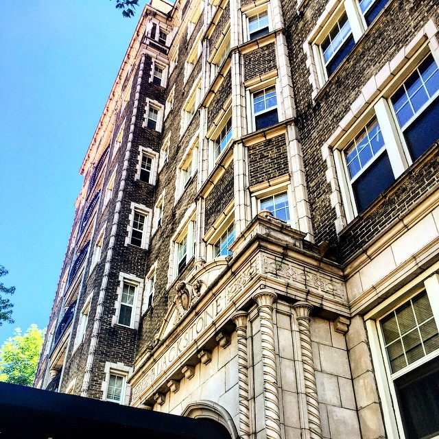 Tall historical apartment building with dark brown brick and white stone. Photo by Instagram user @josh_milesm