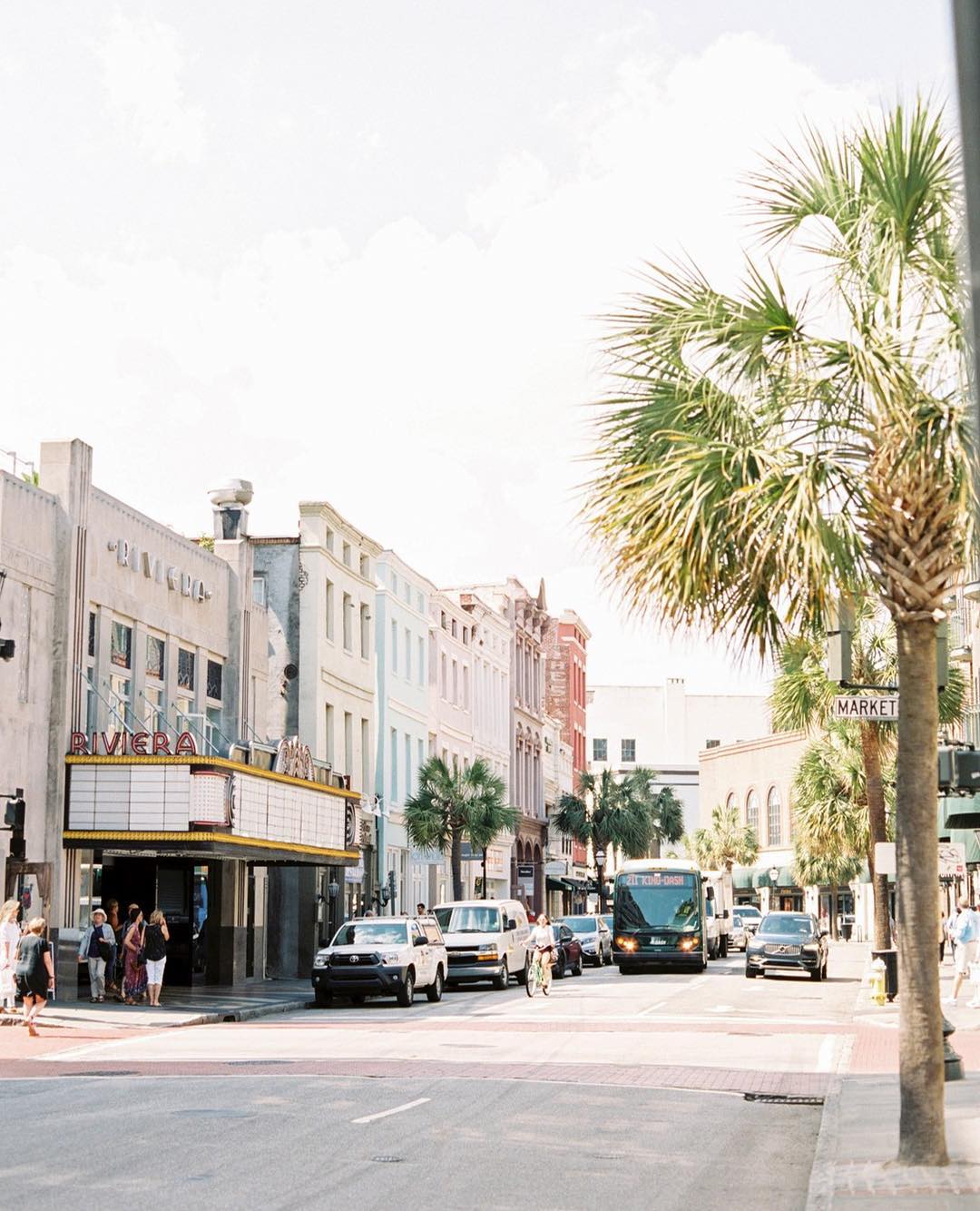 Looking down a downtown street in Charleston with people and cars. Photo by Instagram user @ashleyschurchphotography