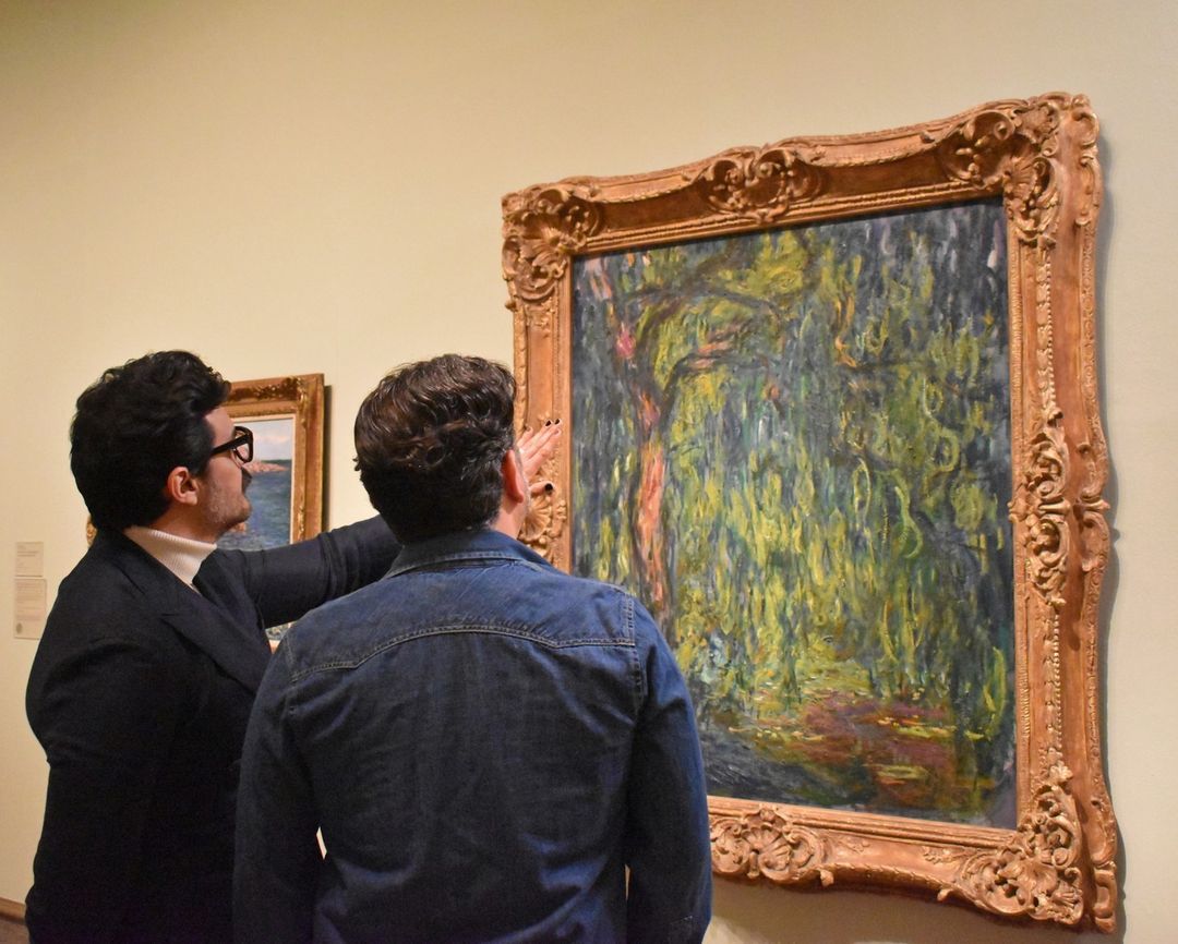Two patrons of the Columbus Museum of Art considering an ornately framed oil painting. Photo by Instagram user @columbusmuseum