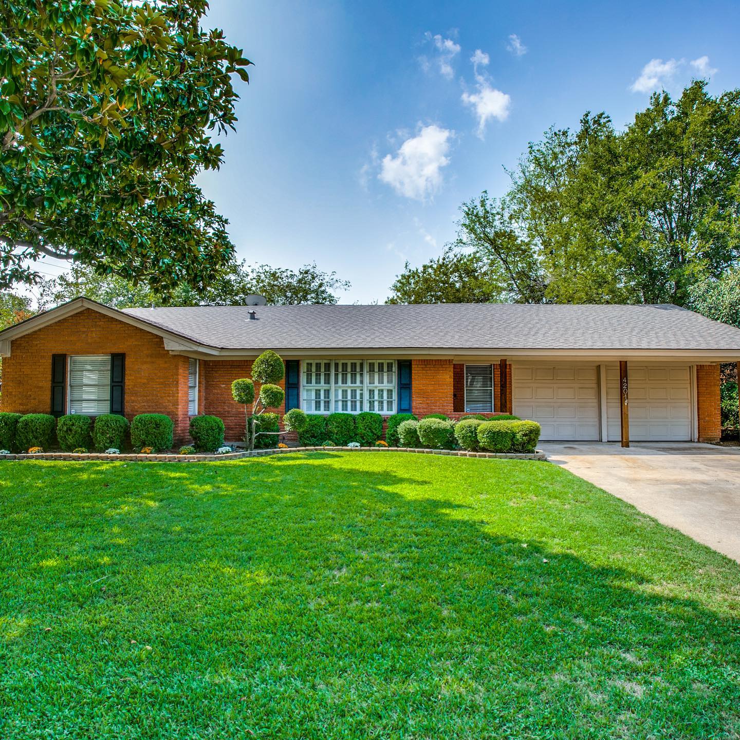 brich ranch style home with green grass