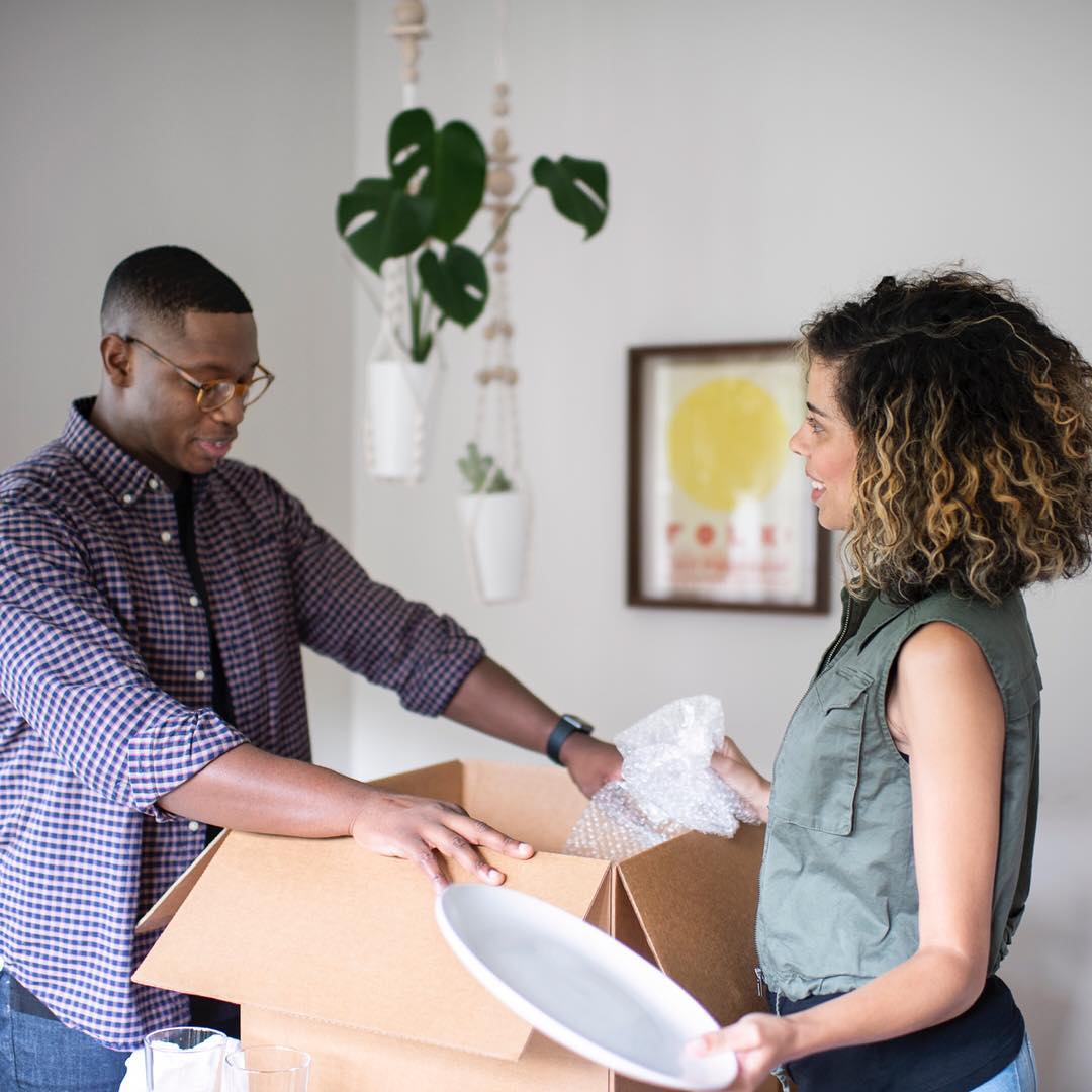 Couple Placing Unneeded Items into Donation Box. Photo by Instagram user @bellhopmoving