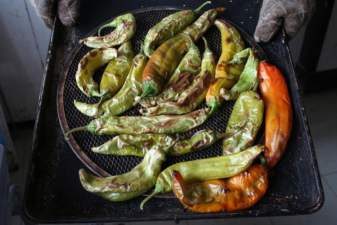 Large hatch chiles roasting on a grill. Photo by Instagram user @visitabq
