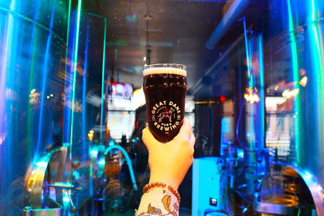 Closeup of woman's arm while holding a pint of dark beer. Photo by Instagram user @greatdanepub