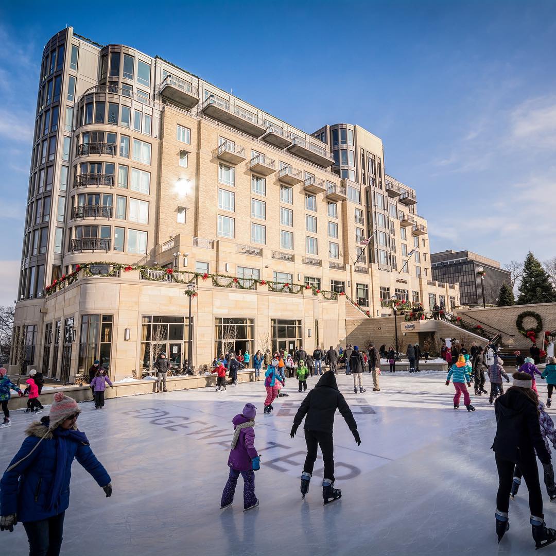 Adults and children ice skating near large building. Photo by Instagram user @visitmadison