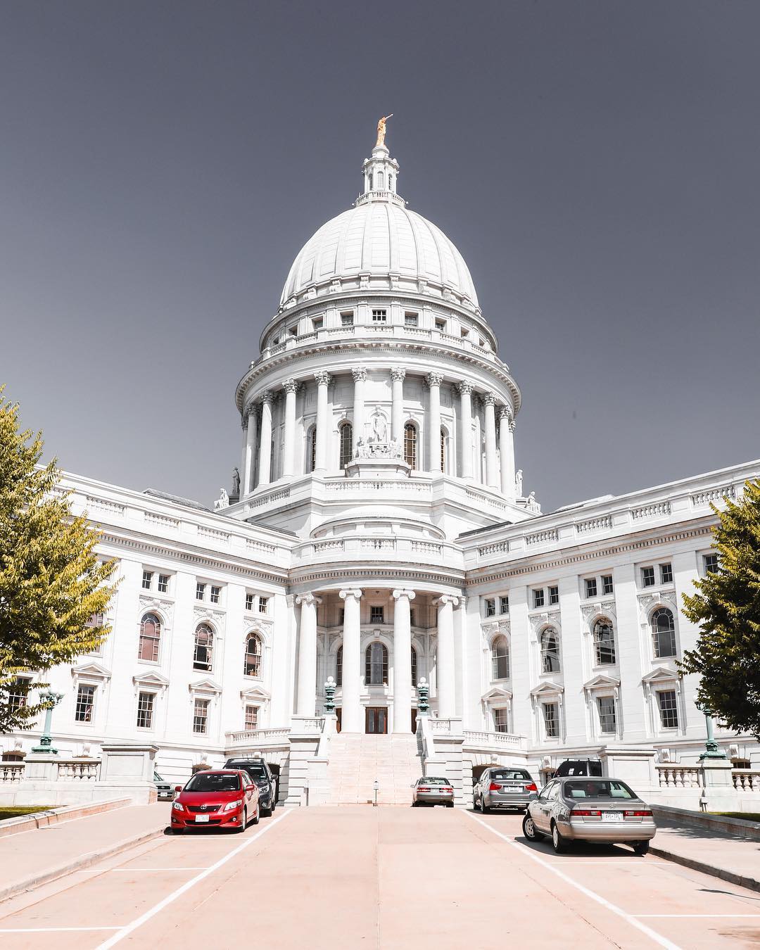 Front view of the Wisconsin capitol with a few cars parked out front. Photo by Instagram user @cityofmadison