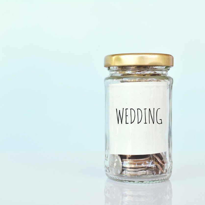 Glass Jar Filled with Coins and Marked for Wedding Savings. Photo by Instagram user @simplelavishweddings
