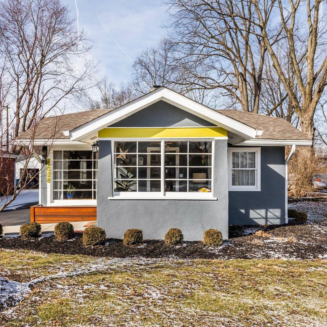 Front of small single-family home with blue-gray stucco and yellow and white trim Photo by Instagram user @matt.meyers.realtor.indy