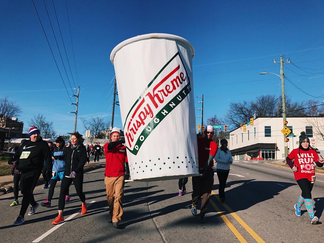 Runners holding a large Krispy Kreme Doughnuts coffee cup during a race. Photo by Instagram user @ncstate
