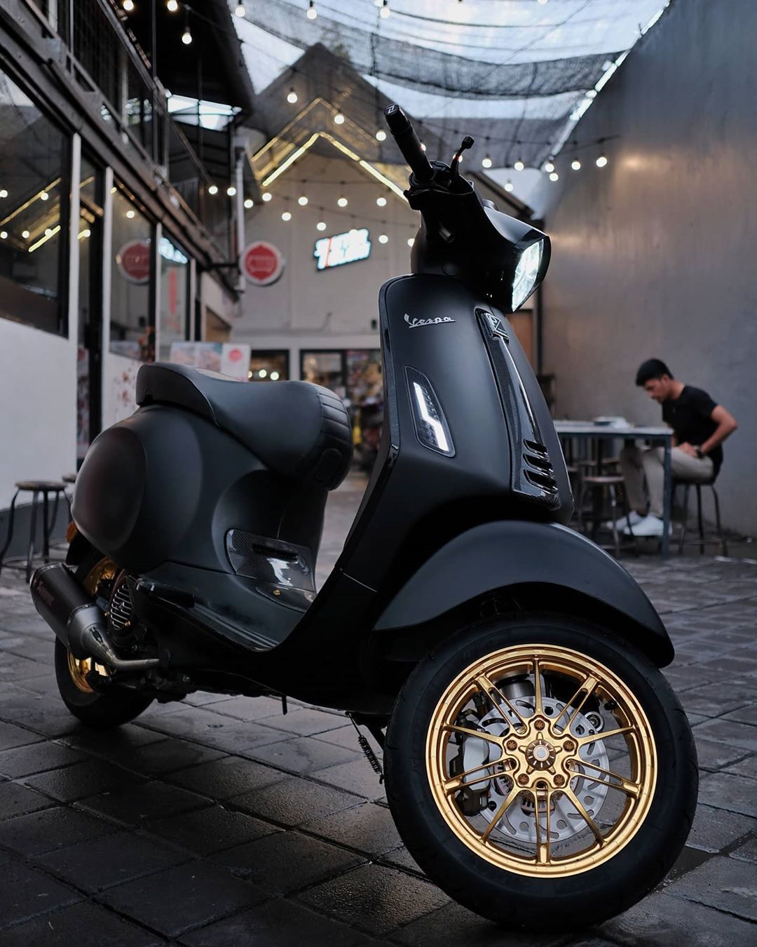 matte black motor scooter with gold rims photo by Instagram user @skuterkoloni