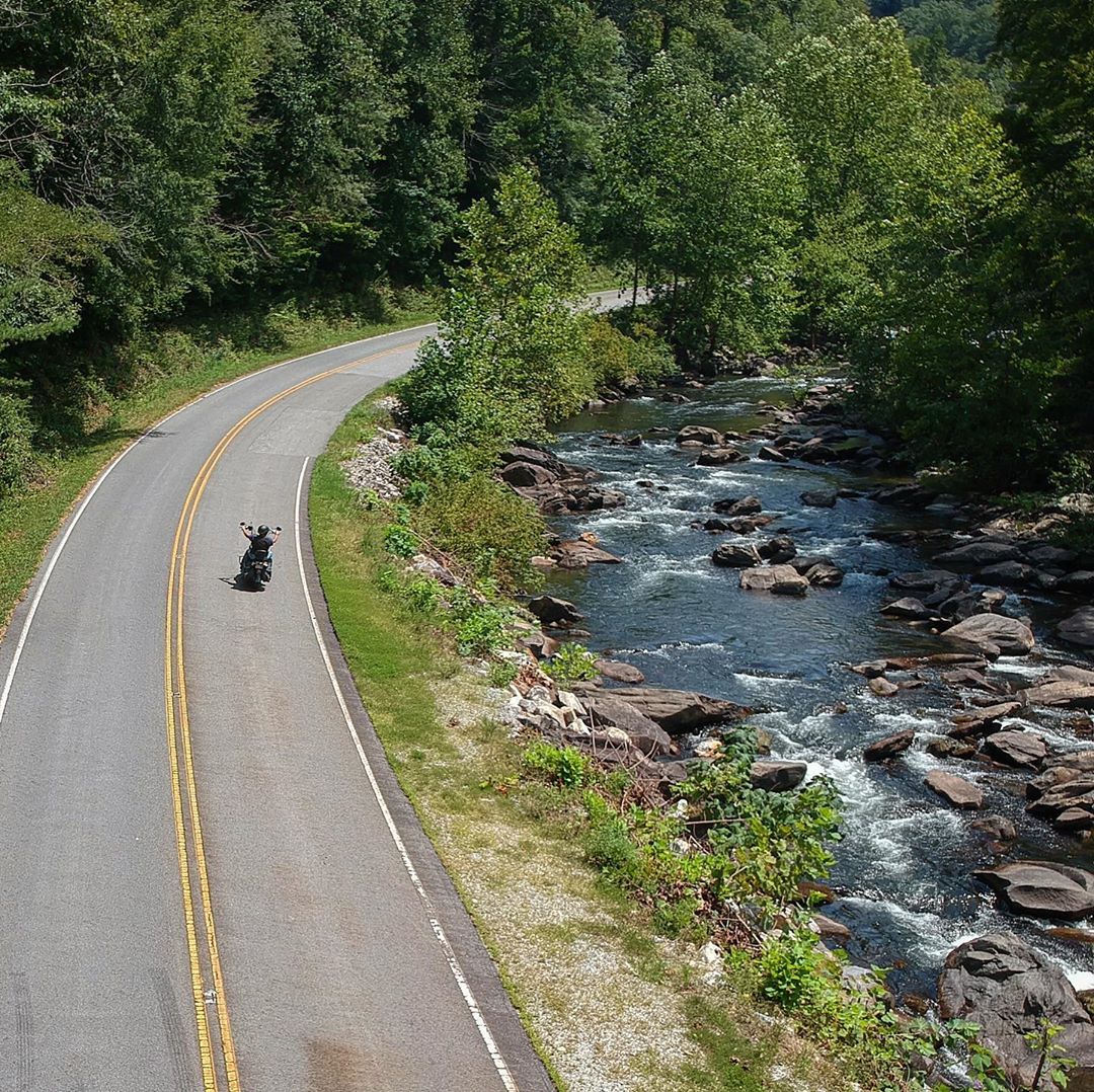 Aerial view of motorcycle on road next to river. Photo by Instagram user @officialtailofthedragon