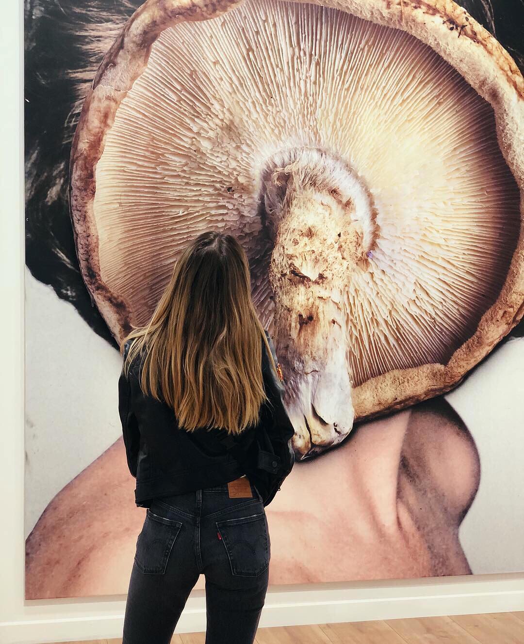 Woman in black looking at mushroom picture at Art Basel in Miami, FL. Photo by Instagram user @seymasubasi