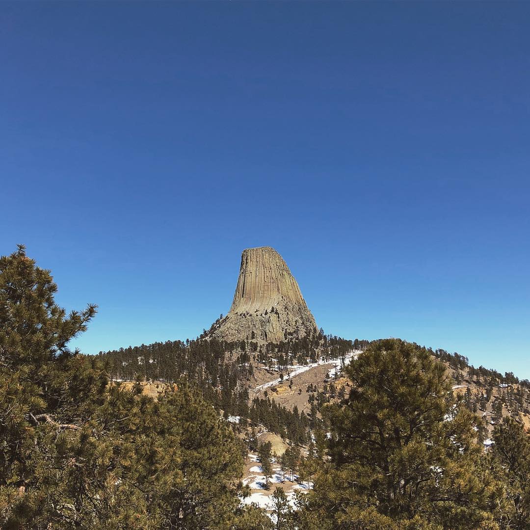 Rock formation at the top of a hill surrounded by trees. Photo by Instagram user @devilstowernps