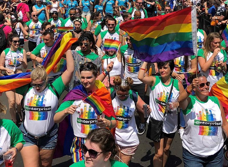 Members of the LGBTQ community marching at miami pride with rainbow flags. Photo by Instagram user @miamibeachpride