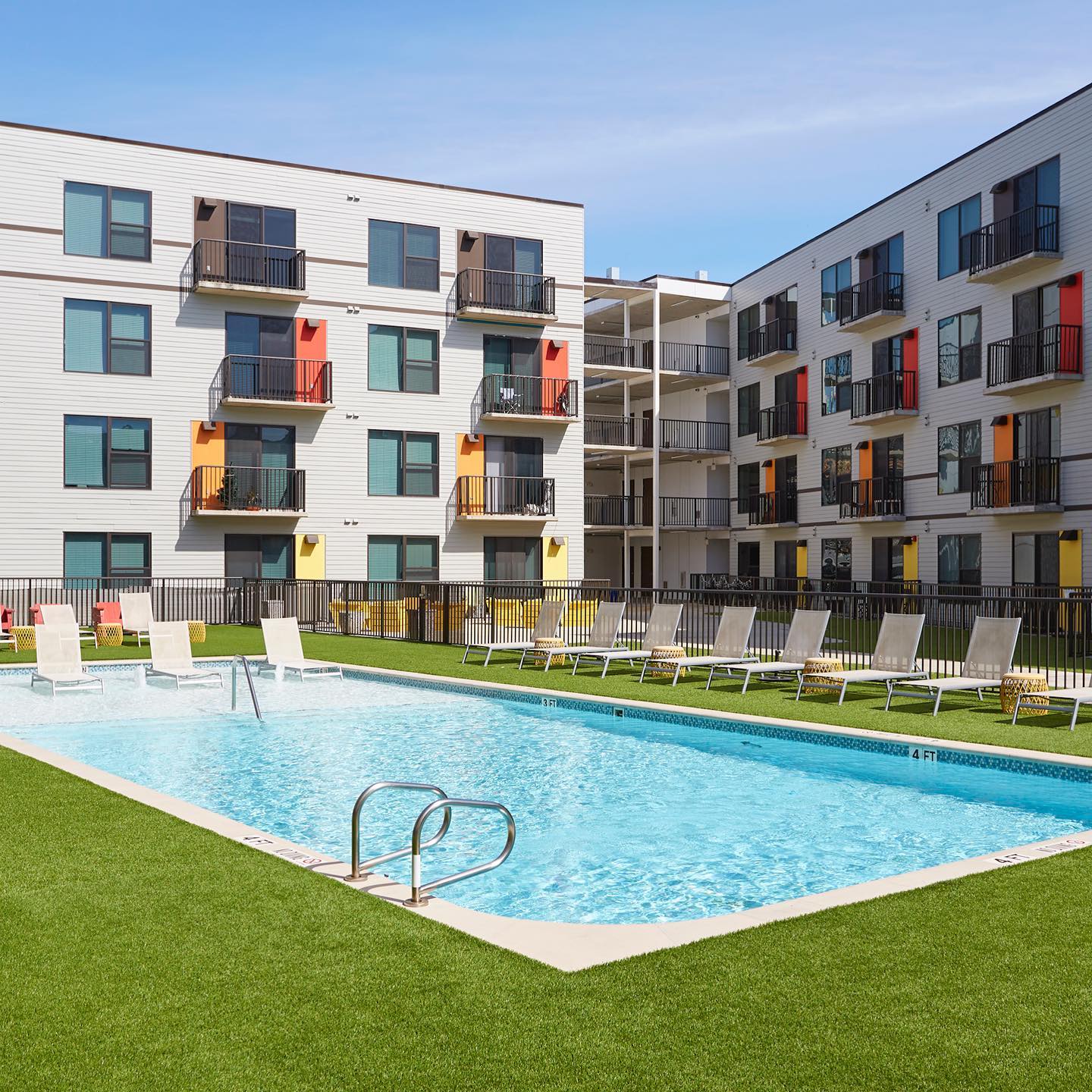 Exterior shot of apartment units in the background featuring a pool in the middle. @midmainlofts