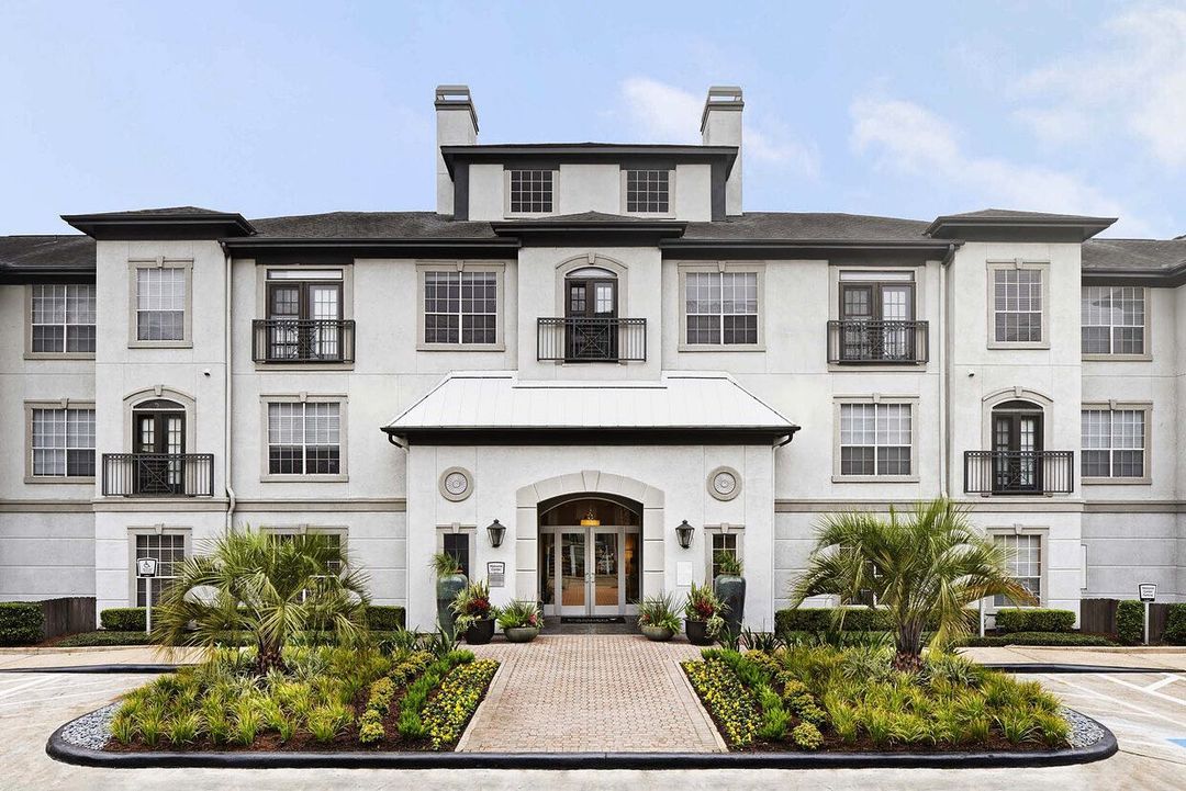 Exterior shot of a Midtown Houston apartment complex with plant life on both sides of a walkway. @camdenmidtown