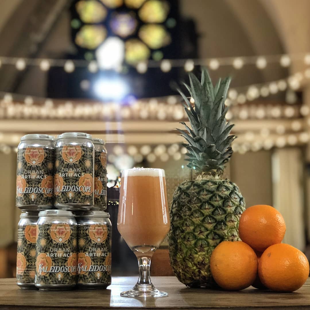 Chalice of beer next to cans and a pineapple at Urban Artifact in Cincinnati, OH. Photo by Instagram use @urbanartifactbeer