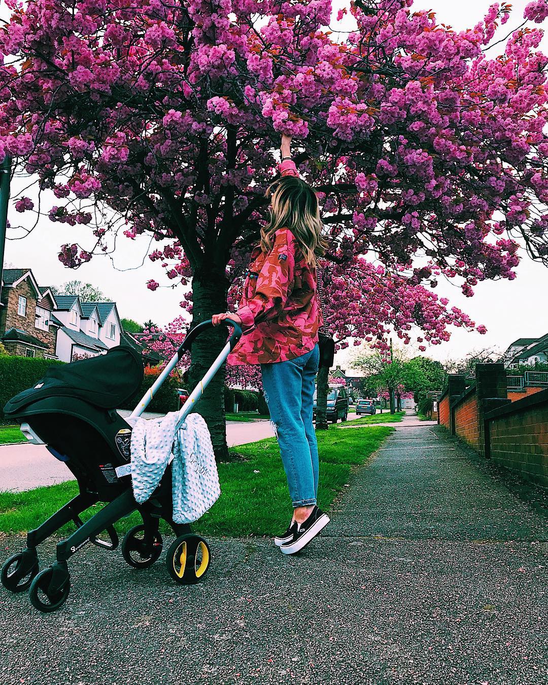 Woman picking pink flowers from a tree. Photo by Instagram user @astonmerrygold