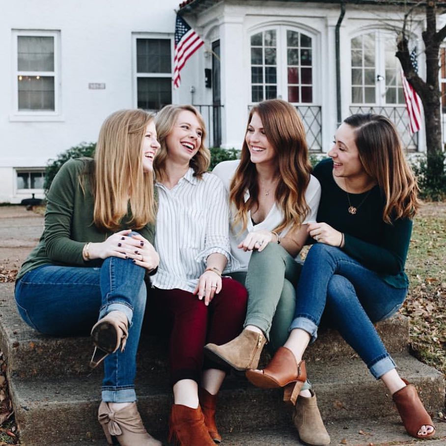 Four women sitting outside laughing. Photo by Instagram user @movingwiththemilitary