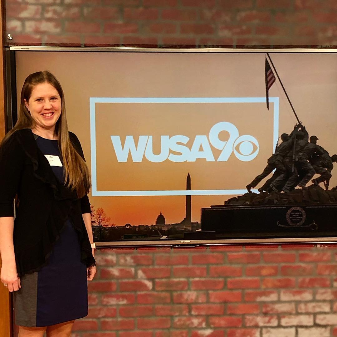 Woman standing next to a news station sign at WUSA 9. Photo by Instagram user @airmantomom