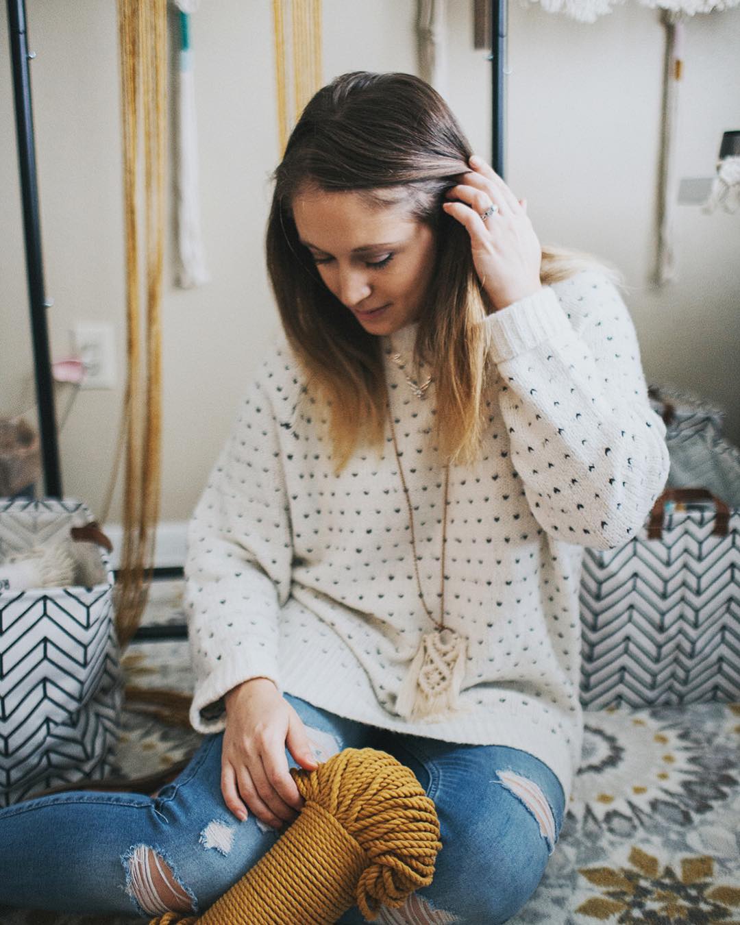 Woman sitting with totes of yarn. Photo by Instagram user @deserthomestudio