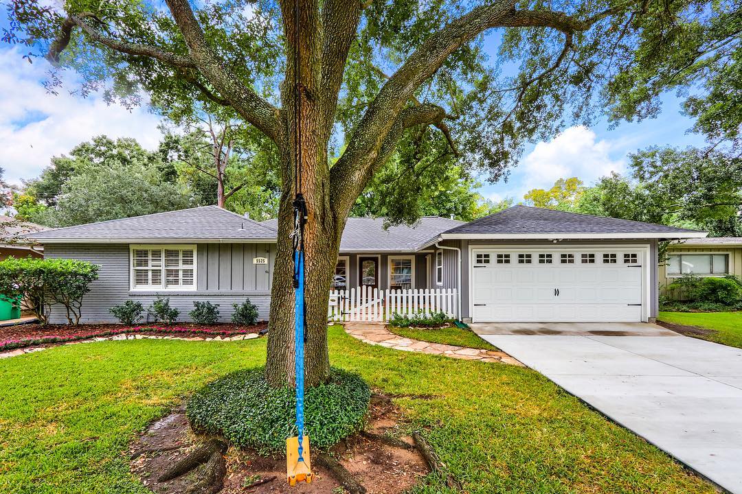 Grey house with white picket fence and swing in the tree in Kingwood, Houston. Photo by Instagram user @lrp_real_estate_photography 