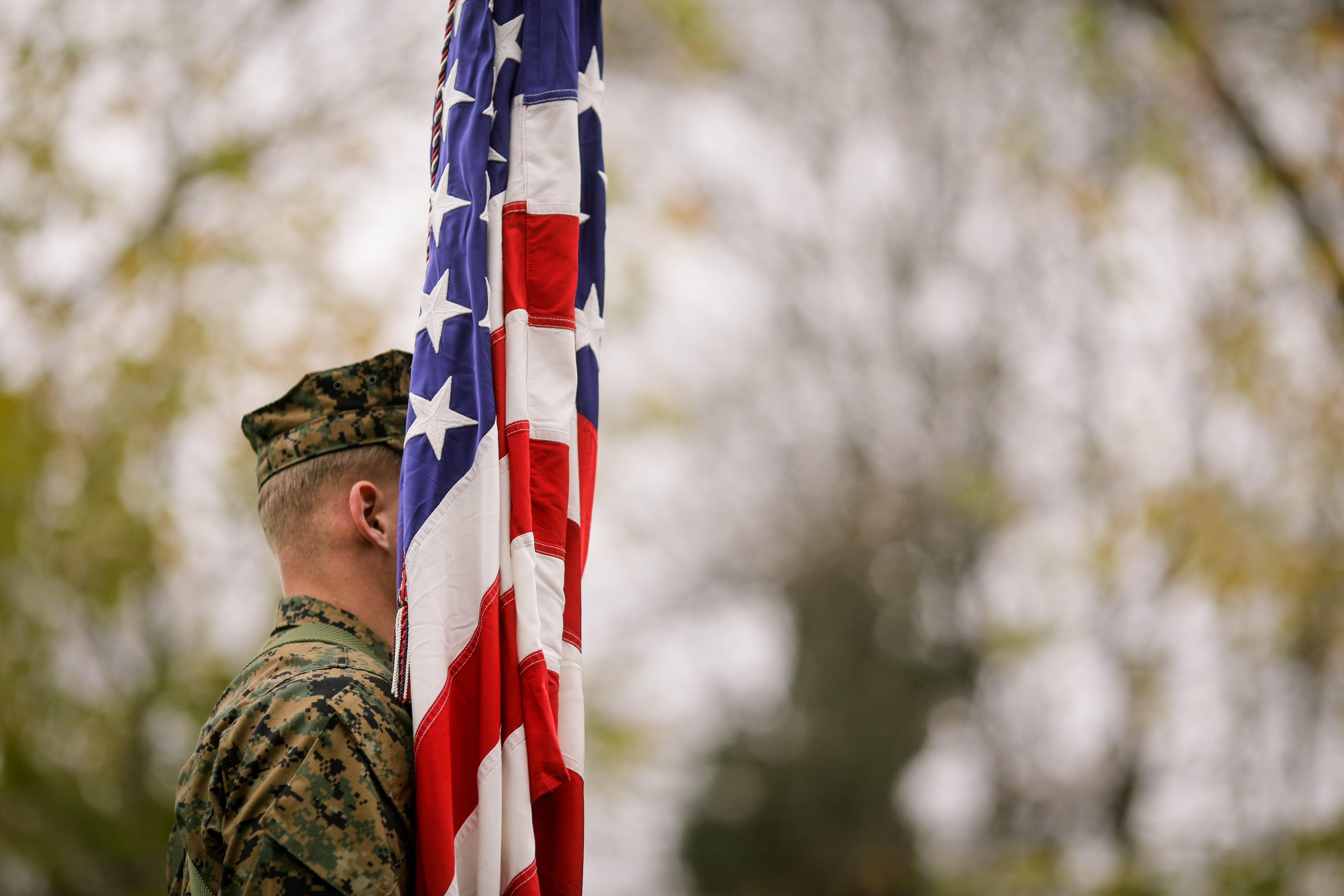 Man in military uniform standing behind US flag