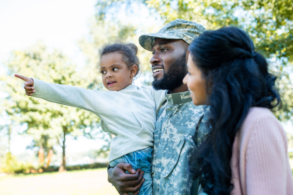 Military family standing together with little daughter pointing.