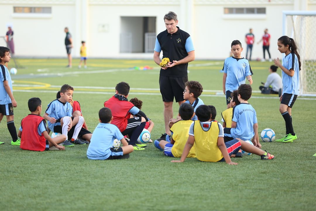 A group of kids sitting around for soccer practice. Photo by Instagram user @starfootballacademy