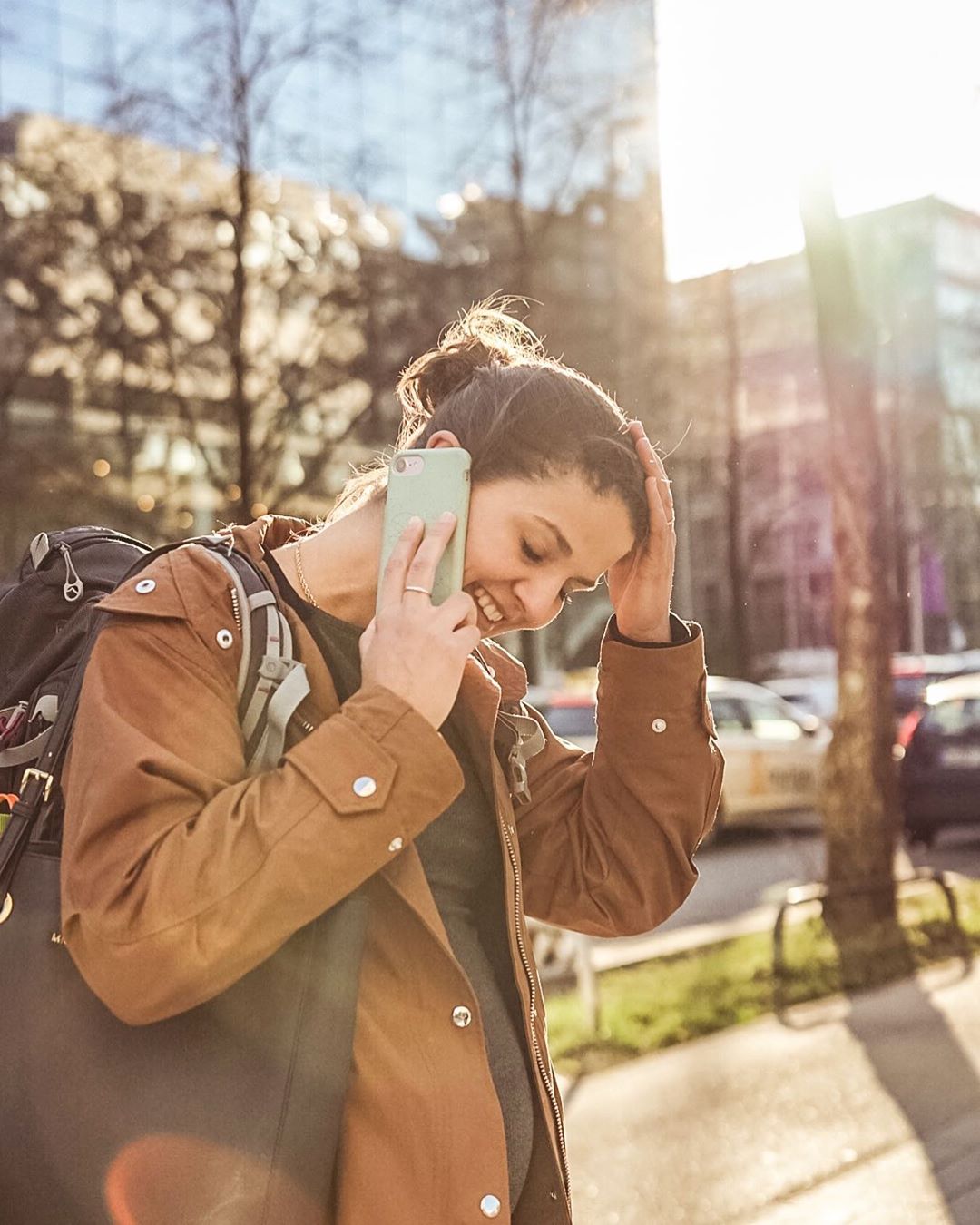 Woman talking on phone in brown jacket. Photo by Instagram user @m_grueneberg