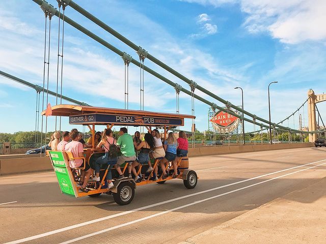 Group of people riding the Pedal Pub party bike across a Minneapolis bridge. Photo by Instagram user @pedalpubtwincities.