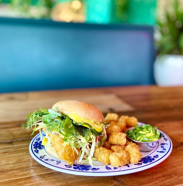 Dinner plate with a turmeric dill filet o fish sandwich and a side of tater tots. Photo by Instagram user @haihaimpls.
