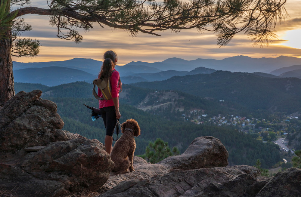 Woman standing at the top of mountain with her dog