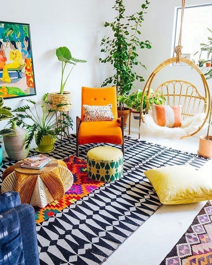 Living room designed in Eclectic style with patterned rug and orange chair and tall house plants. Photo by Instagram user @bohemianhomedecor