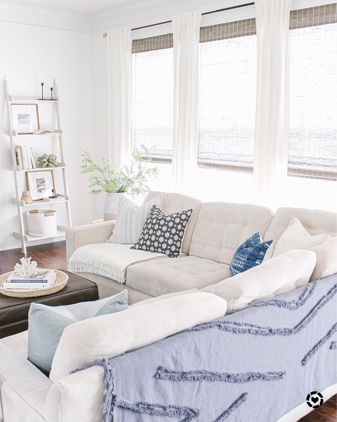 White living room with blue blankets and blue pillows decorated in Coastal style. Photo by Instagram user @caitlinmariedesign