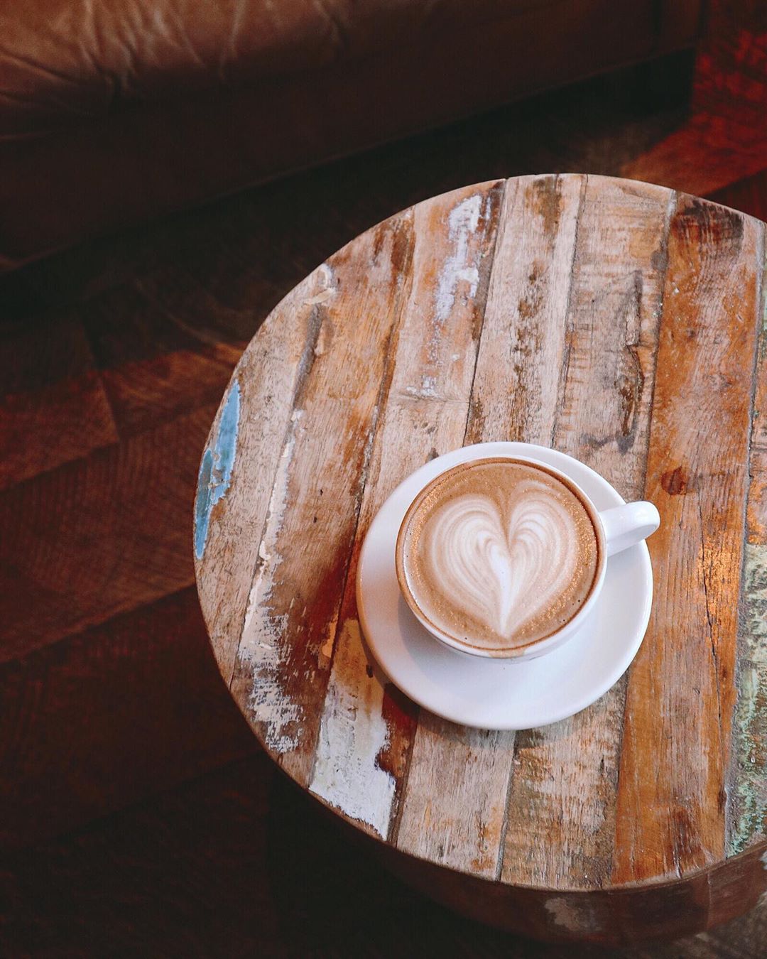 Latte with a heart on it sitting on a wood table. Photo by Instagram user @gloria_fitfatfun