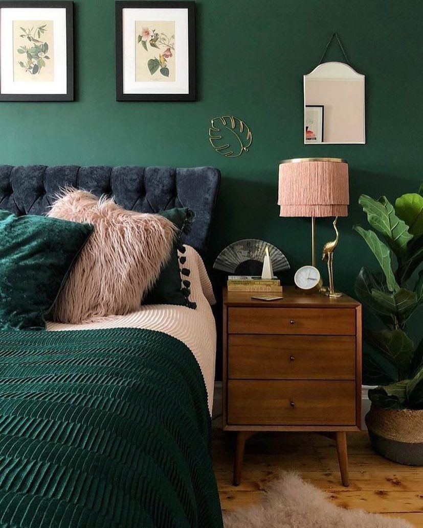 Bedroom with green walls and green bedding with pink lamp. Photo by Instagram user @greenaccentwall