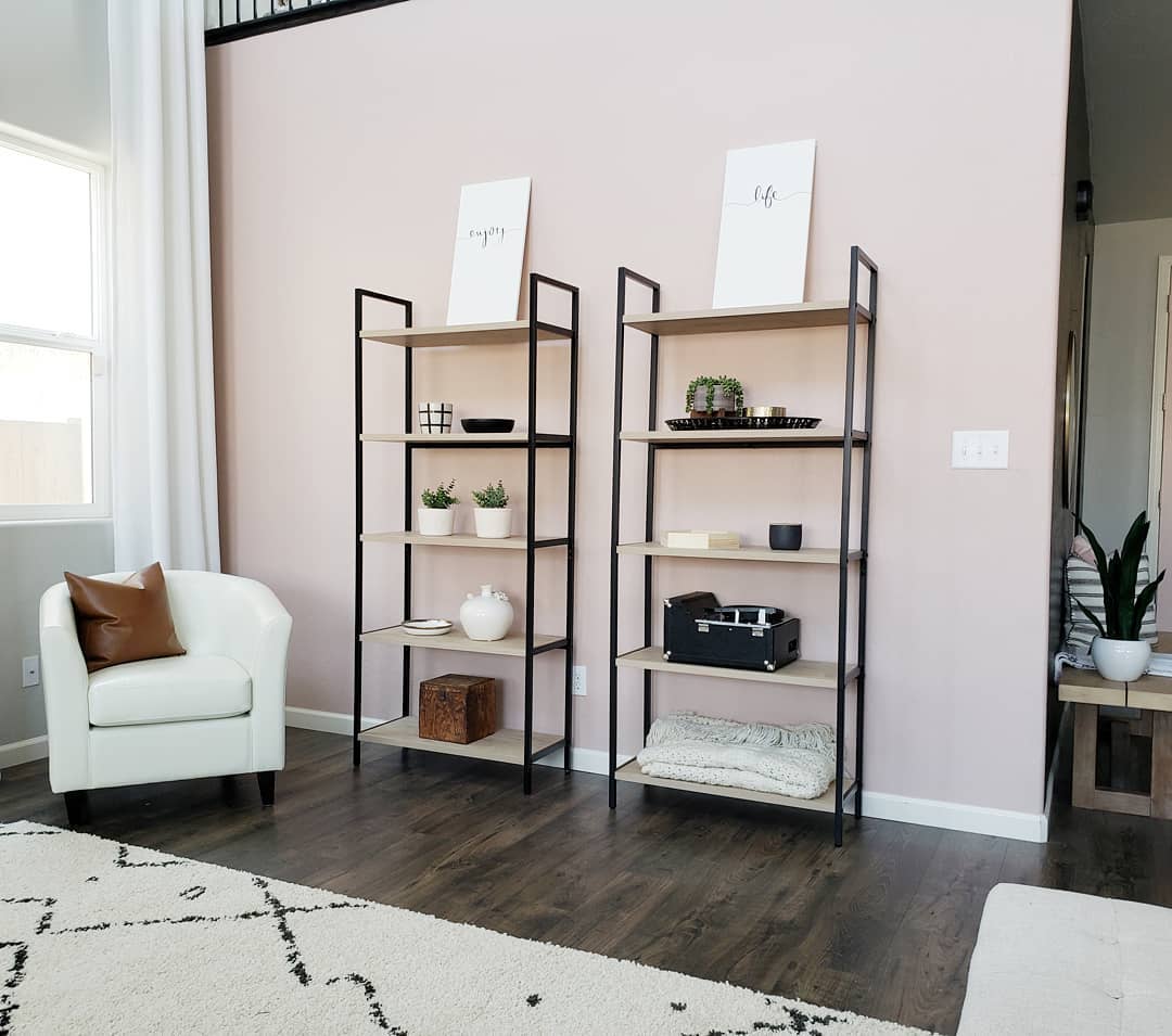 Living room with a custom pink walls and industrial shelves. Photo by Instagram user @taijanellie