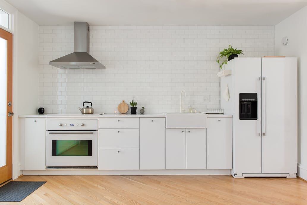 All white kitchen with light wood floors. Photo by Instagram user @_minima_