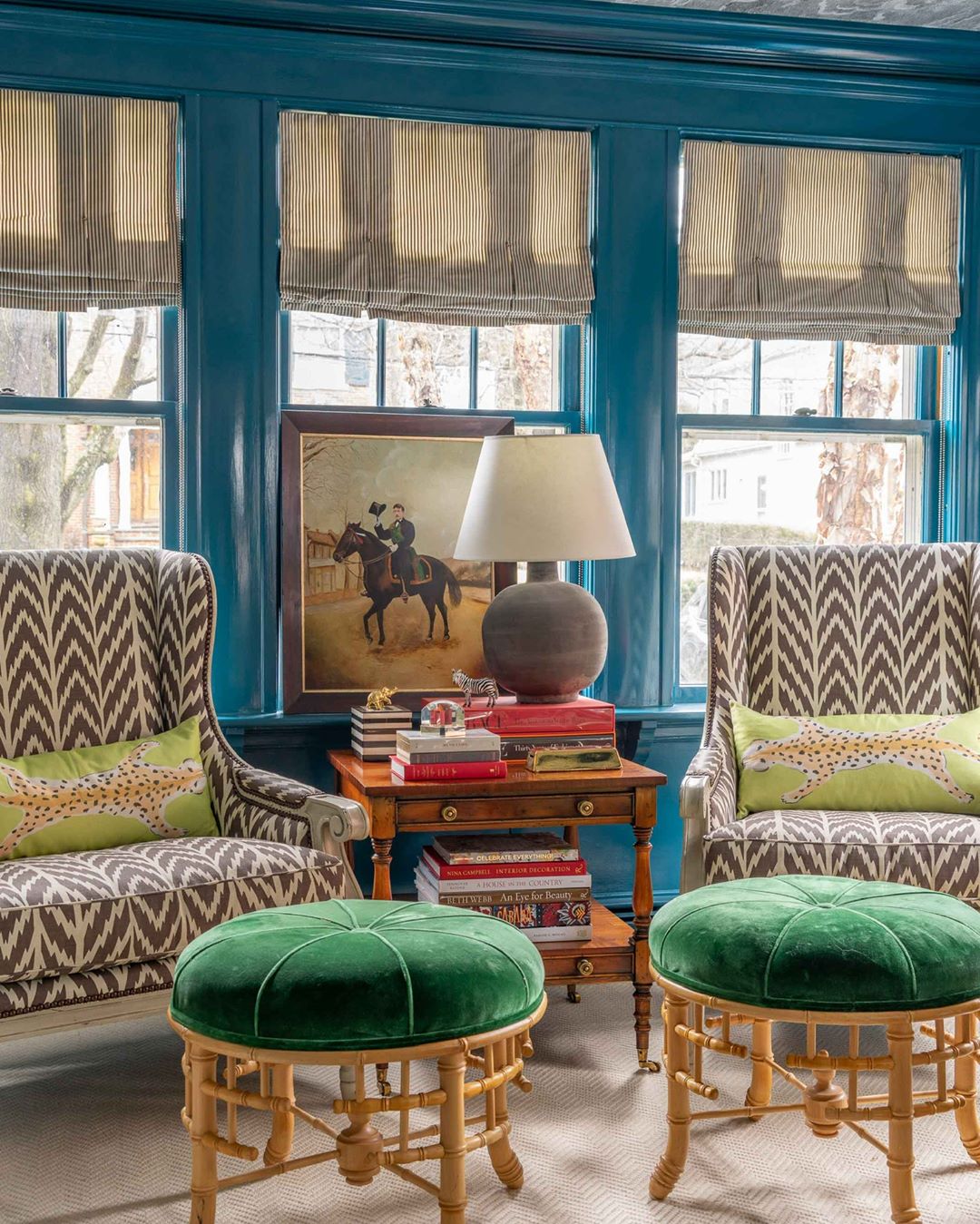 Living room with blue walls and patterned chairs with green stools in Ecelectic design. Photo by Instagram user @lizcaan