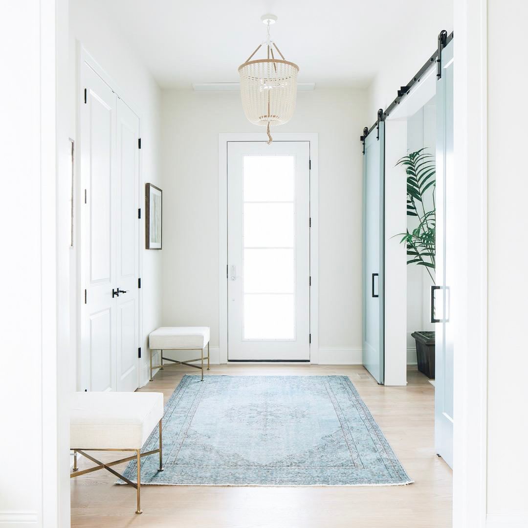 Entryway painted all white with a blue rug. Photo by Instagram user @thegulashop