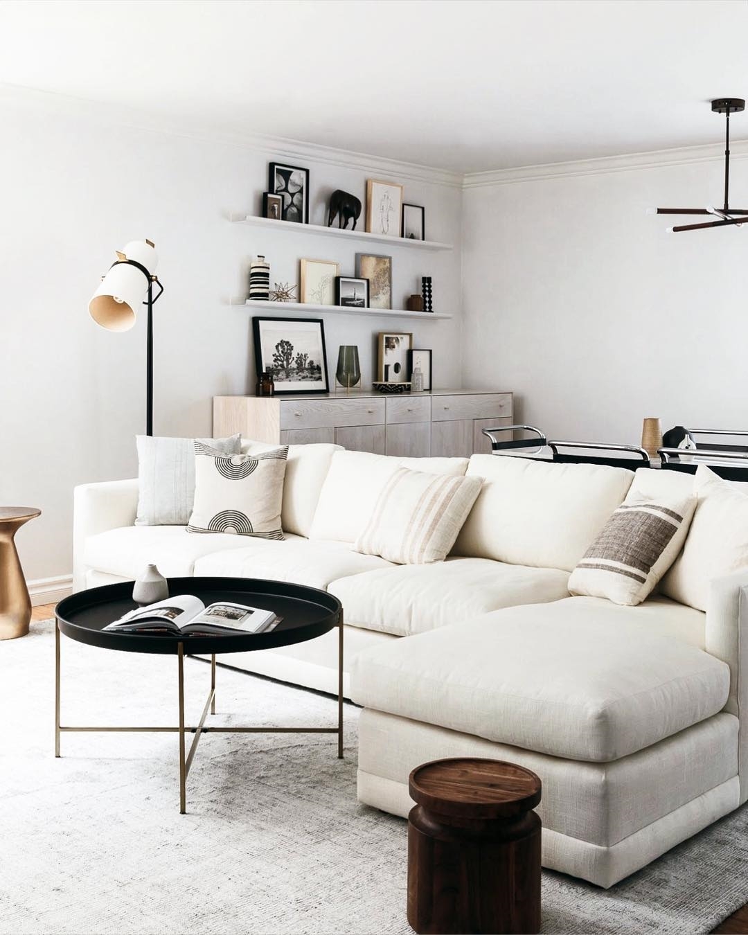 Living designed in Minimalist style with a tan couch and white walls and blush pillows. Photo by Instagram user @mi_property_solutions