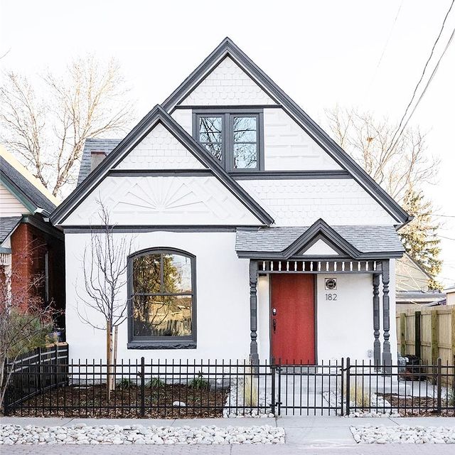 White two story home with black trim and a red door. Photo by Instagram user @katekazell