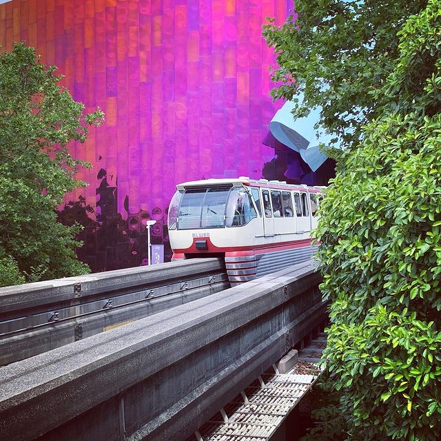 The Seattle Monorail running along the track in front of a purple glass building facade.