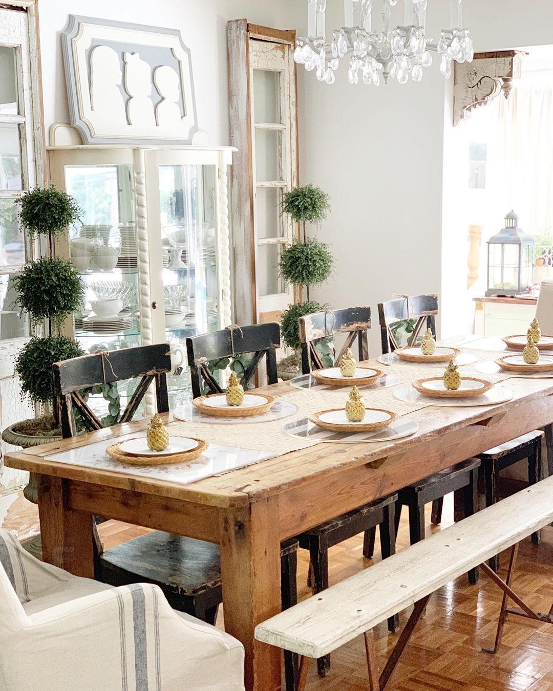 Long wood dining table with plates and gold pineapple statues on them. Photo by Instagram user @robyns_frenchnest