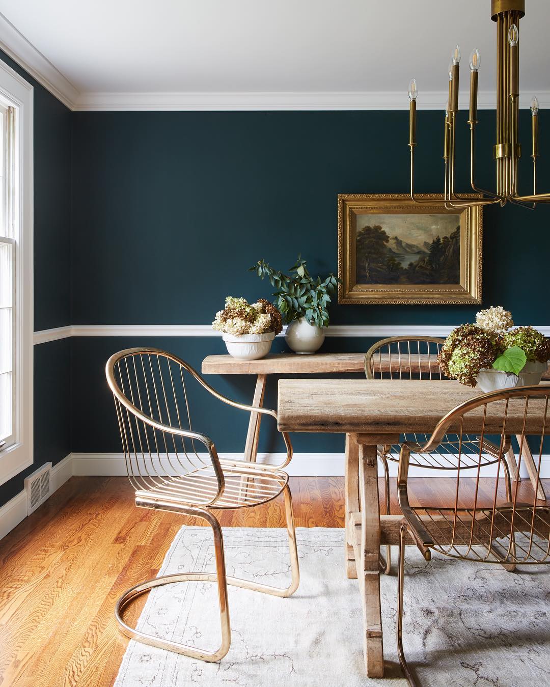 Dining room painted in forest green color with wood table and chairs. Photo by Instagram user @leannefordinteriors