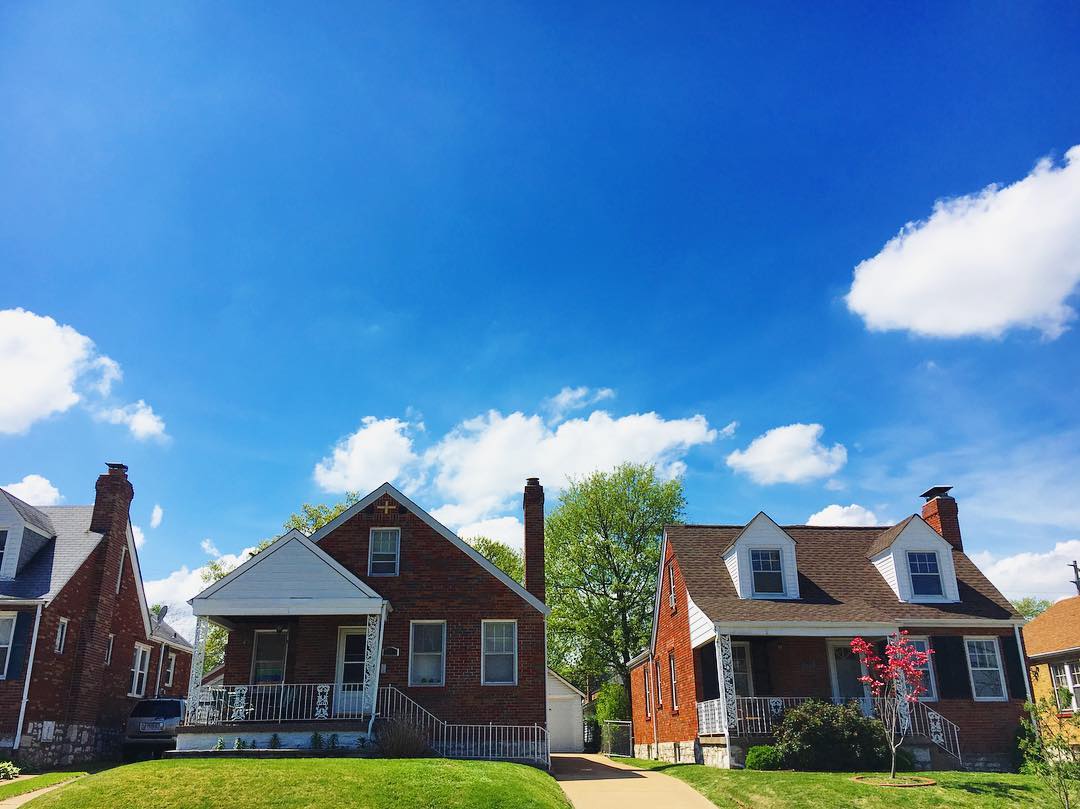 Two brick houses under a blue sky in Franz Park, St. Louis. Photo by Instagram user @emily_m_wasserman
