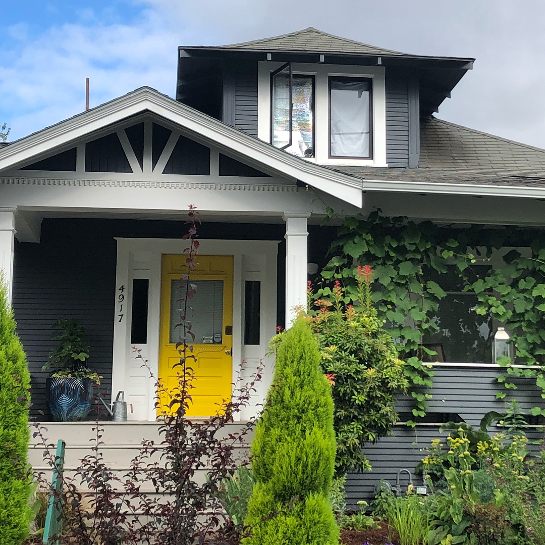 Gray house with white trim and a yellow door in King, Portland. Photo by Instagram user @lizzychun